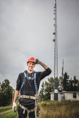 Koşum takımı ayakta telekomünikasyon Tower'da ile Üniformalı erkeklere neşeli teknisyen