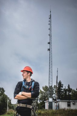 Koşum takımı ayakta telekomünikasyon Tower'da ile Üniformalı erkeklere neşeli teknisyen