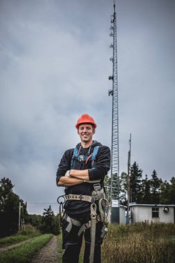 Koşum takımı ayakta telekomünikasyon Tower'da ile Üniformalı erkeklere neşeli teknisyen