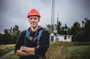 Silah ile neşeli genç adam ayakta kolları telekomünikasyon Kulesi arka plan üzerinde çarpı işareti olan çarpı işareti.