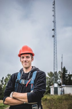 Silah ile neşeli genç adam ayakta kolları telekomünikasyon Kulesi arka plan üzerinde çarpı işareti olan çarpı işareti.