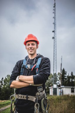 Koşum takımı ayakta telekomünikasyon Tower'da ile Üniformalı erkeklere neşeli teknisyen