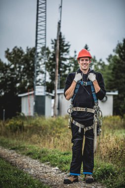 Koşum takımı ayakta telekomünikasyon Tower'da ile Üniformalı erkeklere neşeli teknisyen
