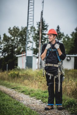 Koşum takımı ayakta telekomünikasyon Tower'da ile Üniformalı erkeklere neşeli teknisyen
