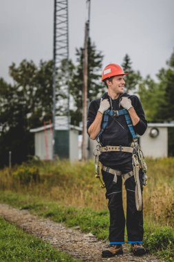 Koşum takımı ayakta telekomünikasyon Tower'da ile Üniformalı erkeklere neşeli teknisyen