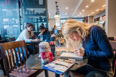 Montreal, Kanada - 1 Aralık 2017: Montreal Starbucks bir kağıt yastık üzerinde çizim genç kadın.