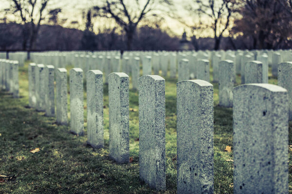 Back of Army Headstone and Graveyard Cemetery during a Sad Dark Cloudy Day of Autumn.