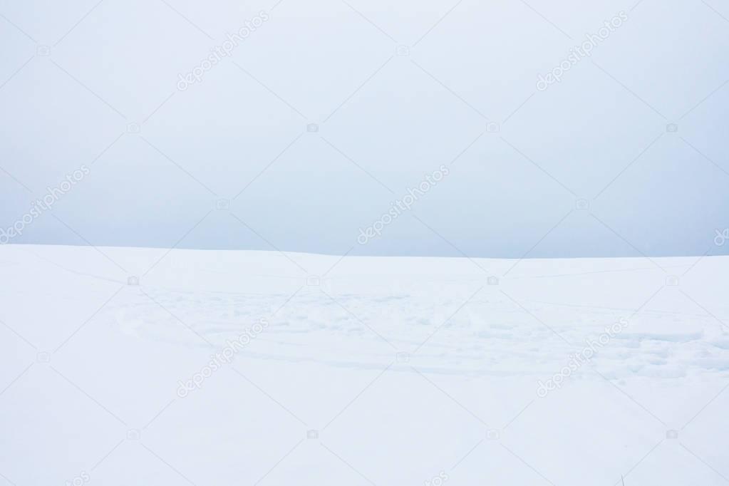 Soft Minimaliste Landscape of Snow Field with Snowmobile Tracks and Cloudy Sky