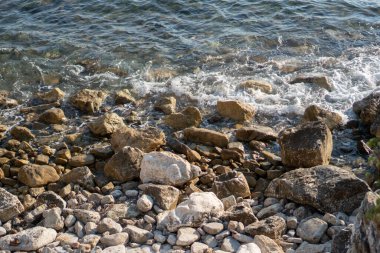 Sahildeki kayalara vuran deniz dalgalarının üst görüntüsü. Köpük ve sıçrama..