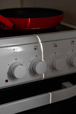 Boş kırmızı tava beyaz bir elektrikli sobanın üzerinde duruyor.