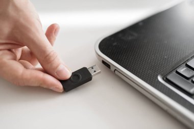 Adamın biri USB flaş belleği eliyle bilgisayara takıyor.