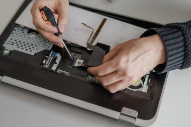 Bir adam dizüstü bilgisayarı söker. Bilgisayar servisi ve tamir konsepti. Onarım atölyesinde dizüstü bilgisayar parçalanıyor, yakın plan. Elektronik geliştirme, elektronik cihaz onarımı