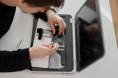 Bir adam dizüstü bilgisayarı söker. Bilgisayar servisi ve tamir konsepti. Onarım atölyesinde dizüstü bilgisayar parçalanıyor, yakın plan. Elektronik geliştirme, elektronik cihaz onarımı