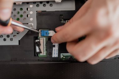 Bir adam dizüstü bilgisayarı söker. Bilgisayar servisi ve tamir konsepti. Onarım atölyesinde dizüstü bilgisayar parçalanıyor, yakın plan. Elektronik geliştirme, elektronik cihaz onarımı