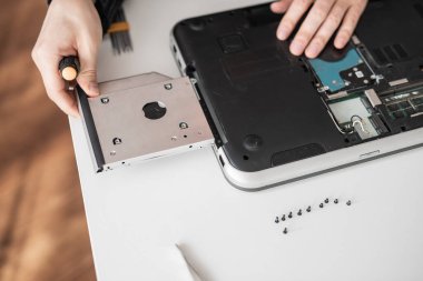 Bir adam dizüstü bilgisayarı söker. Bilgisayar servisi ve tamir konsepti. Onarım atölyesinde dizüstü bilgisayar parçalanıyor, yakın plan. Elektronik geliştirme, elektronik cihaz onarımı