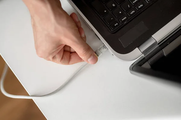 Man connects network lan cable to laptop with his hand. Close up shot, white background