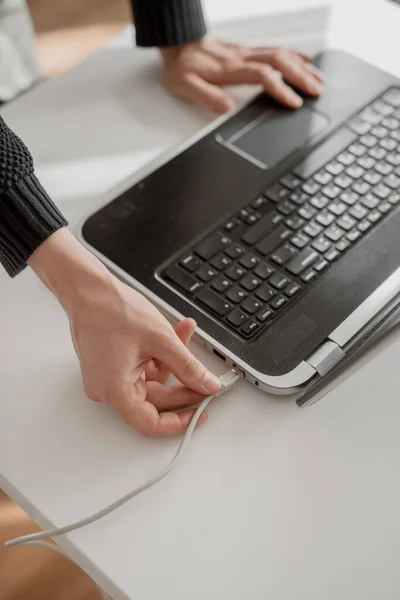 Man connects network lan cable to laptop with his hand. Close up shot, white background