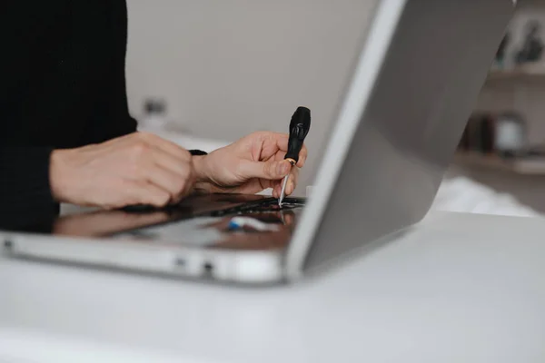 A man disassembles a laptop. Computer service and repair concept. Laptop disassembling in repair shop, close-up. Electronic development, electronic device fixing