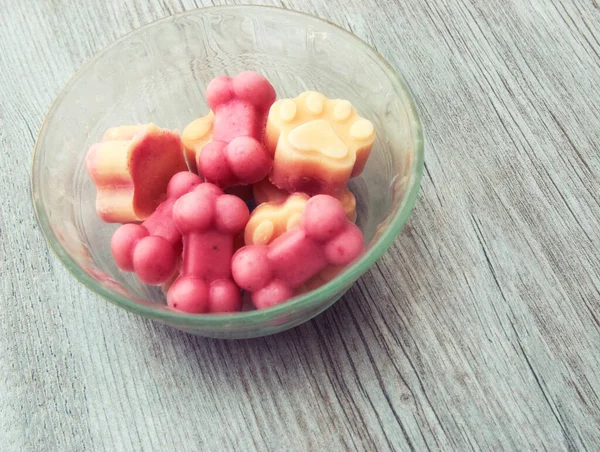 Cold frozen yogurt dog treats in a bowl on a hot summer day with wooden background