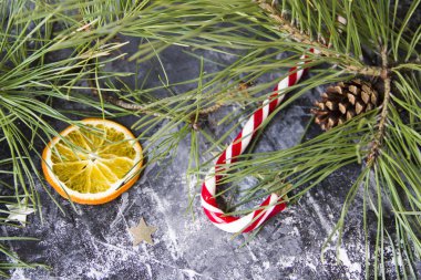 Noel arkaplanda köknar ağacı kuru portakal, gümüş yıldızlar ve koyu arkaplanda Noel şekeri kamışı var.