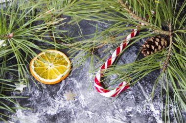 Noel arkaplanda köknar ağacı kuru portakal, gümüş yıldızlar ve koyu arkaplanda Noel şekeri kamışı var.