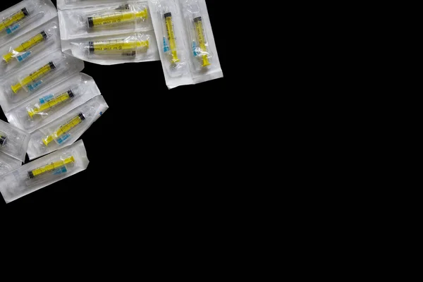 Medical needle & syringe packs on black background, flat lay