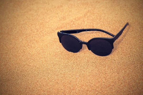 Sunglasses closeup on the sandy coast — Stock Photo, Image