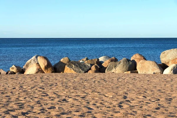 Praia de areia e grandes pedras em terra perto da água — Fotografia de Stock