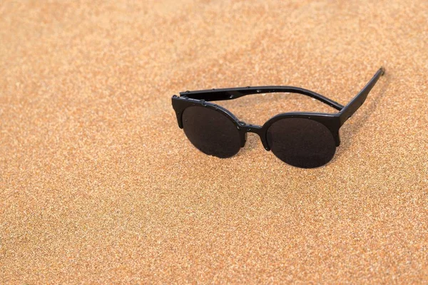 Sunglasses closeup on the sandy coast — Stock Photo, Image