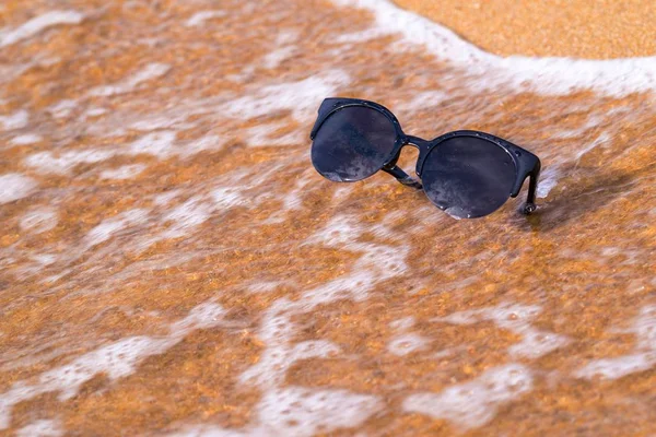 Sonnenbrille und Sandküste mit Welle — Stockfoto