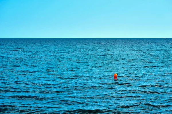 Uma Pequena Bola Vermelha Bóia Primeiro Plano Mar Azul Claro — Fotografia de Stock