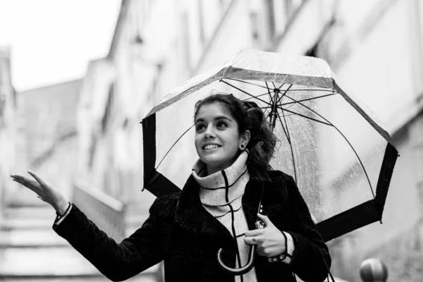 Joven morena juega a tocar las gotas de lluvia bajo un paraguas transparente en un día lluvioso en Cáceres — Foto de Stock