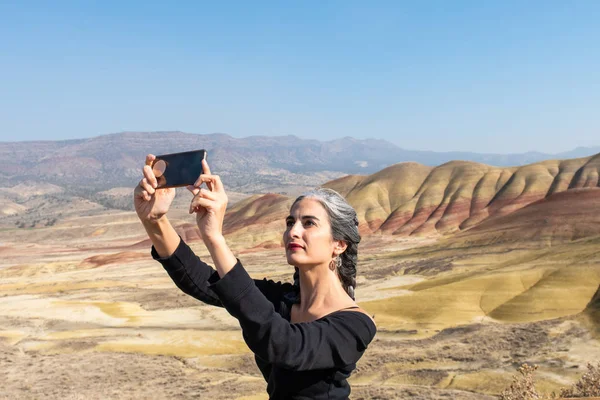 Egy fiatal barna hajú, szürke szálakkal szelfiket készít a Painted Hillsben. — Stock Fotó