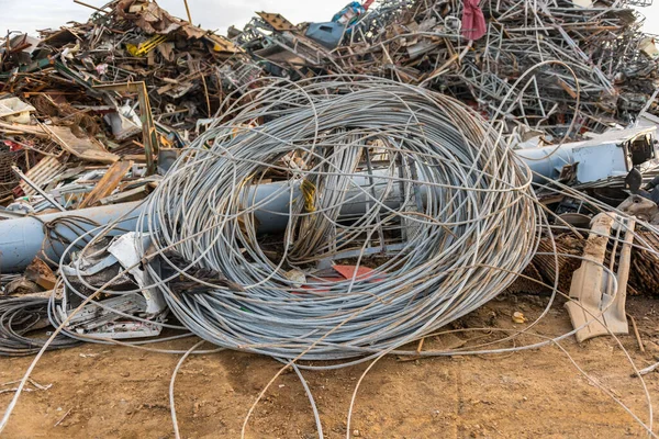 Enorme bobina de cuerda de alambre junto a montañas de escombros en un depósito de chatarra —  Fotos de Stock