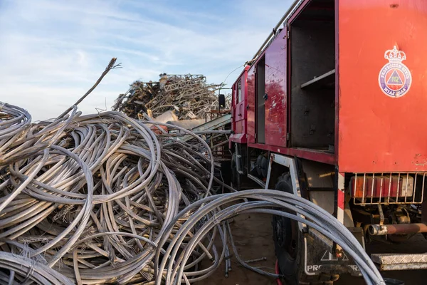 Un camión de protección civil junto a un montón de bobinas de cable en un depósito de chatarra —  Fotos de Stock