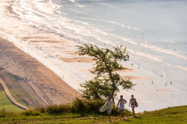 Sörf tahtası olan bir grup genç, Zarautz plajındaki kamp alanına geri dönüyor.