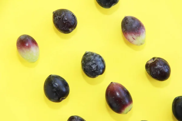 Natürliche frische schwarze Oliven auf gelbem Hintergrund — Stockfoto