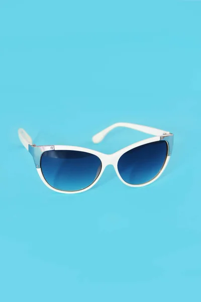 Lunettes de soleil dans un cadre en plastique blanc et verres bleus sur fond bleu — Photo