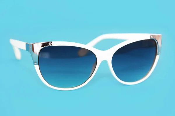 Óculos de sol em uma moldura de plástico branco e lentes de óculos azuis em um fundo azul — Fotografia de Stock