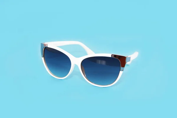 Sluneční brýle v bílém plastovém rámu a modré brýle čočky na modrém pozadí — Stock fotografie