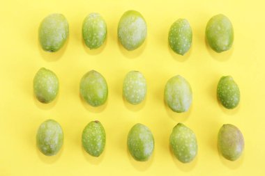 Sarı zemin üzerinde doğal yeşil zeytinler.