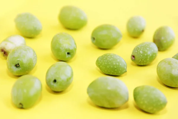 Přírodní zelené čerstvé olivy na žlutém pozadí — Stock fotografie