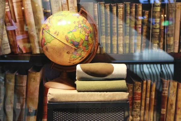 Globus und Kleidung im Schrank auf dem Hintergrund von Büchern — Stockfoto