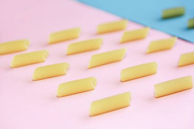 natural long tubular pasta on a pink and blue background