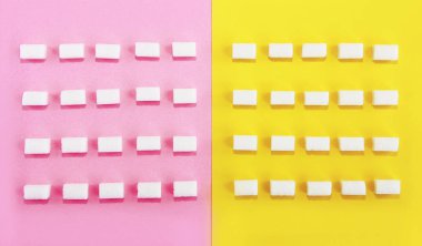 Beyaz, doğal, saf şeker küpleri pembe sarı arka planda.