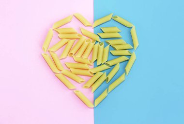 Pembe arkaplanda doğal sarı uzun makarnadan yapılmış bir kalp.