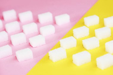 Pembe zemin üzerinde beyaz doğal rafine şeker parçaları