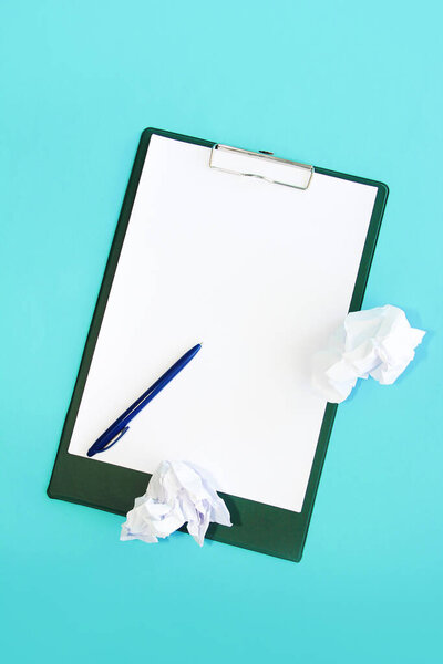 канцелярские ручки, листы мятой белой бумаги на фоне держателя бумаги
