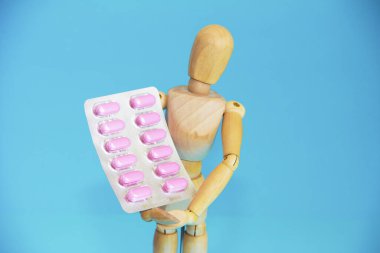 Ahşap sarı manken pembe bir ilaç taşıyor.