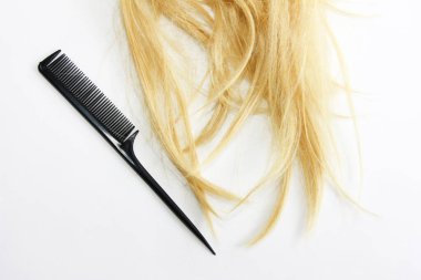 Doğal kıvrımlı, buruşuk sarı bir bukle ve siyah bir tarak.